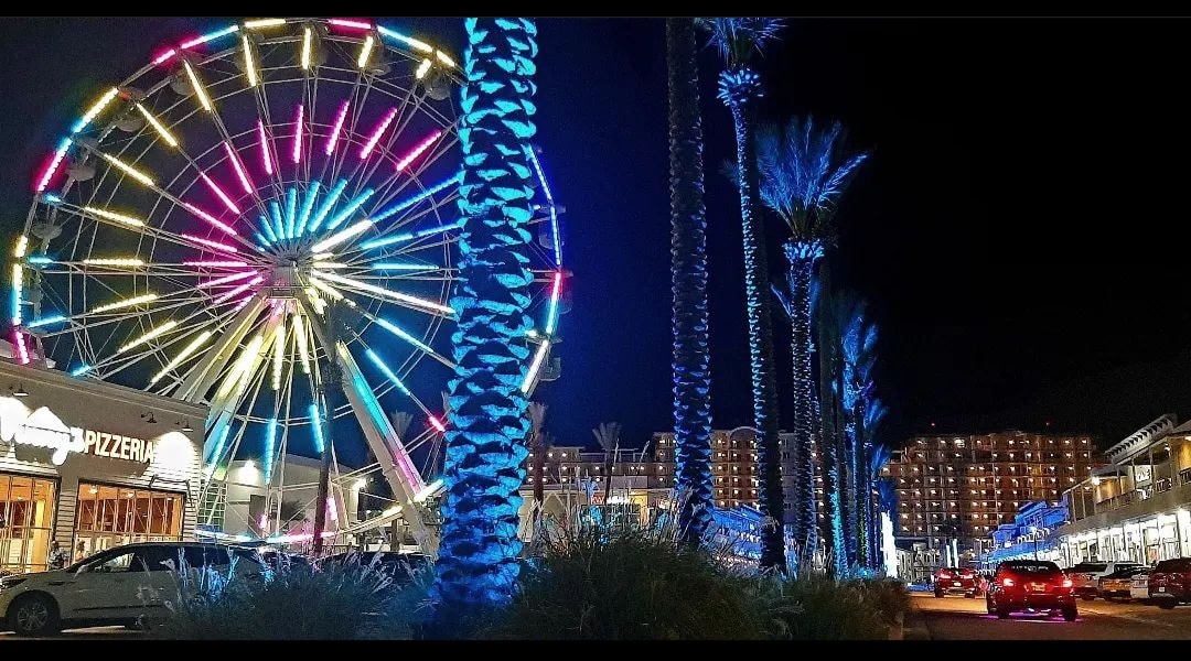 The illuminated Ferris wheel and palm-lined Main Street at The Wharf in Orange Beach, Alabama
